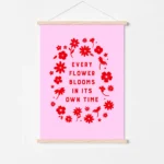 “every flower blooms in its own time” inspirational quote with floral design in red hues - poster hanger