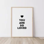 Timber framed black print with 'You Are So Loved' message on floorboards
