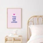 Framed pink print with 'You Are So Loved' message in bedroom